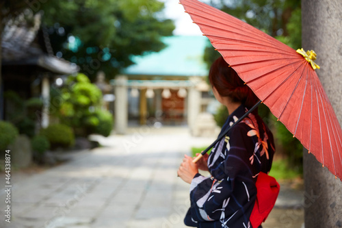 神社の参道に立つ、傘をさした浴衣の女性 photo
