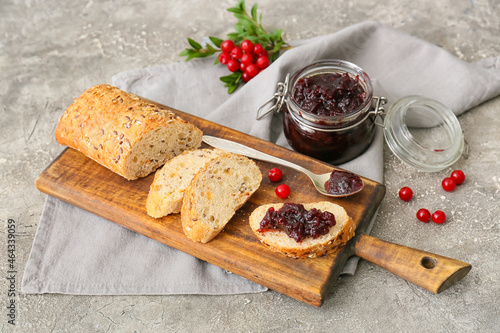 Wooden board of tasty toasts with lingonberry jam on grey background