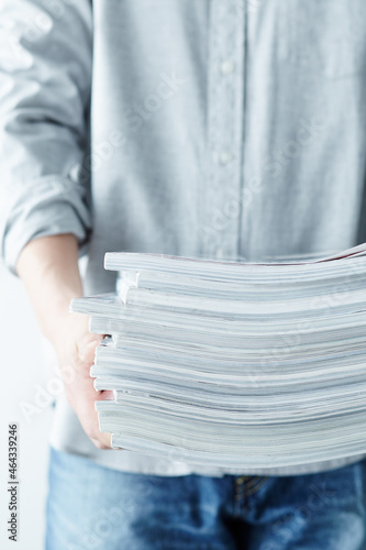 積み重なった雑誌を持つ人