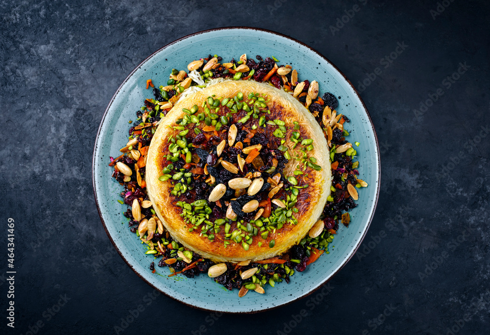 Traditional Persian tahdig jeweled javaher polow bride basmati rice with dried fruits and berries served as top view on a Nordic design plate with copy space