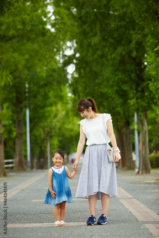木が立ち並んだ道の真ん中に佇む母と娘 Stock Photo Adobe Stock