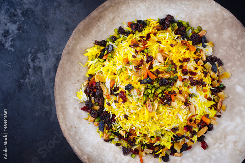 Traditional Persian tahdig jeweled javaher polow bride basmati rice with dried fruits and berries served as top view on a rustic design plate with copy space left photo