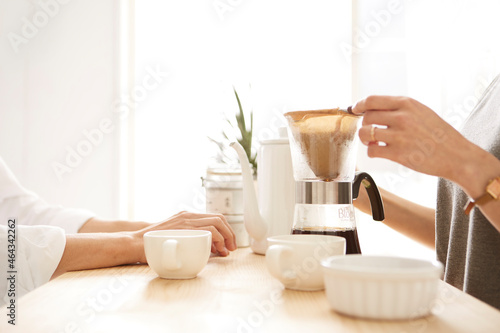 キッチンカウンターでコーヒーを注ぐ男女の手元