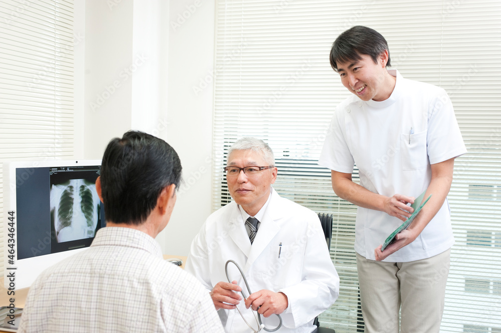 老人患者を診察する中高年の医師と男性看護師 老人患者を診察する中高年の医師と男性看護師