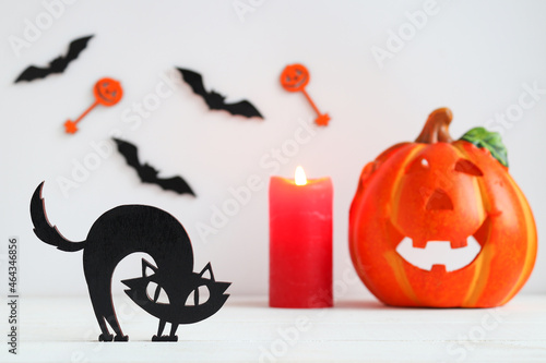 Halloween card with black cat, candle, Jack-o-latern and bats. Selective focus photo