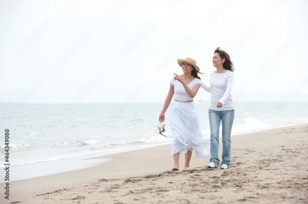 海辺で砂浜を歩く母と娘 海辺で砂浜を歩く母と娘