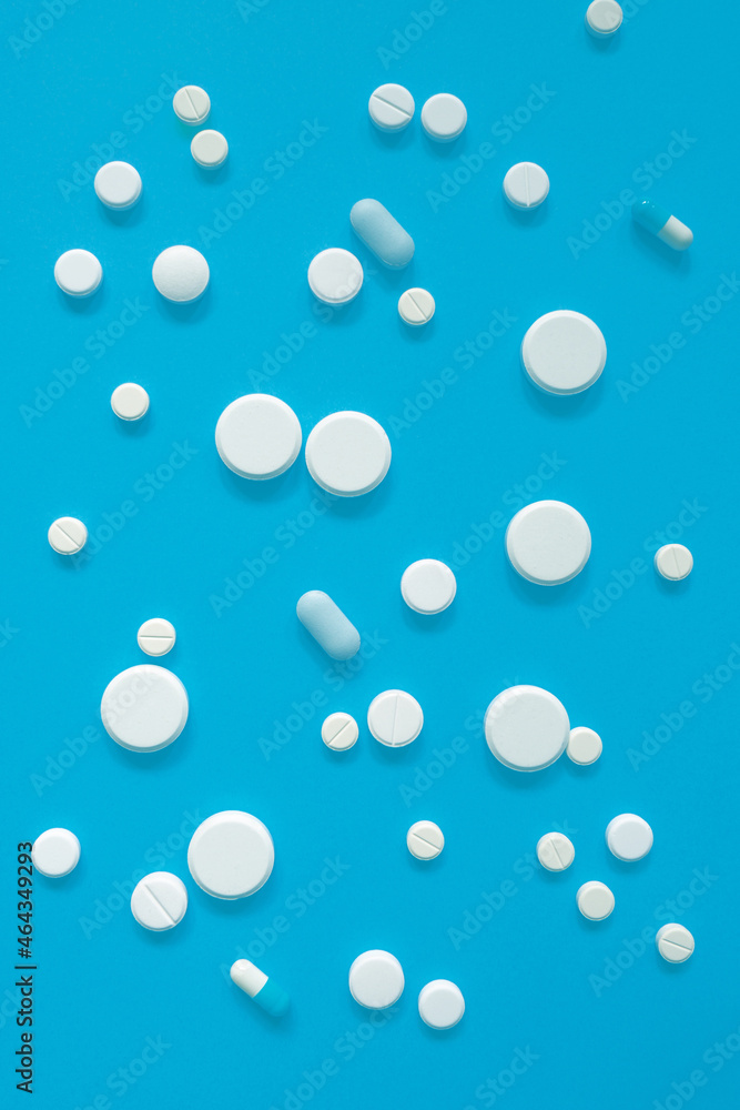 White medicines or pills on blue background for a design on a medical topic