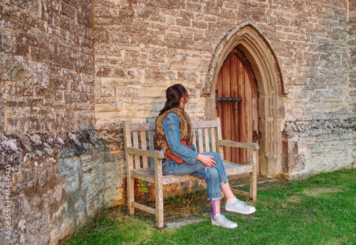 a person sitting on a bench against the wall of the old church