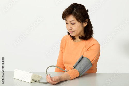 血圧計で測定する中年女性 photo