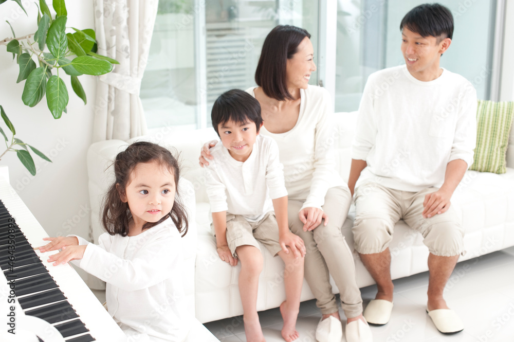 ピアノを弾く女の子とソファに座る家族