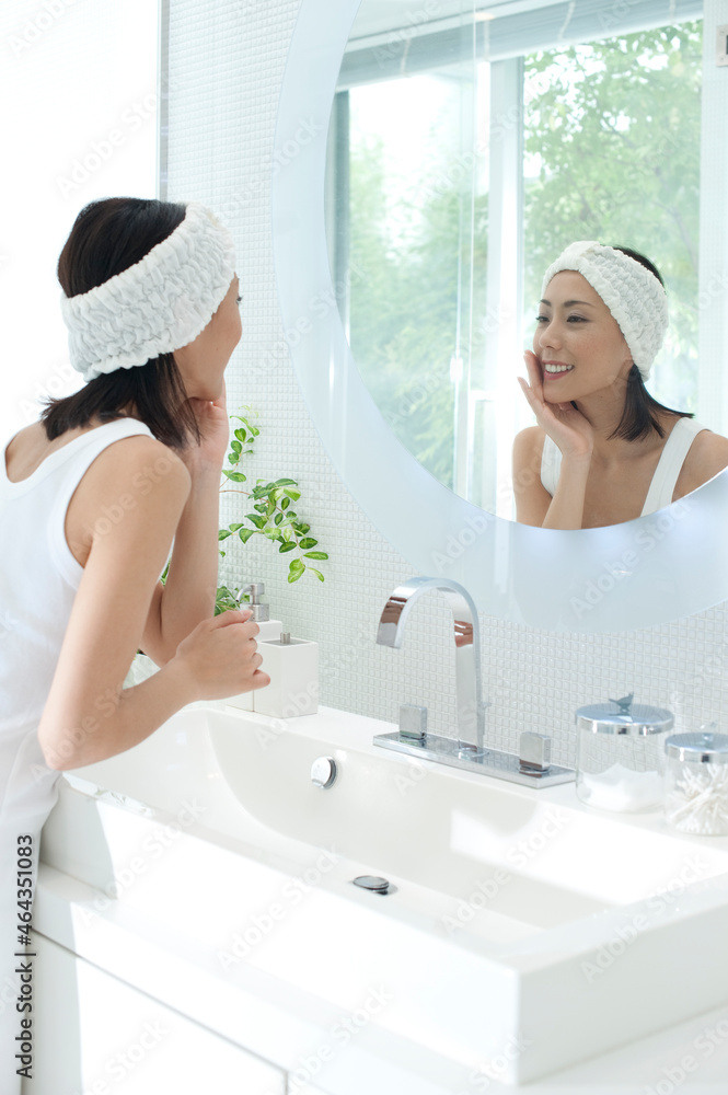 洗面台の鏡を見てお化粧をする女性