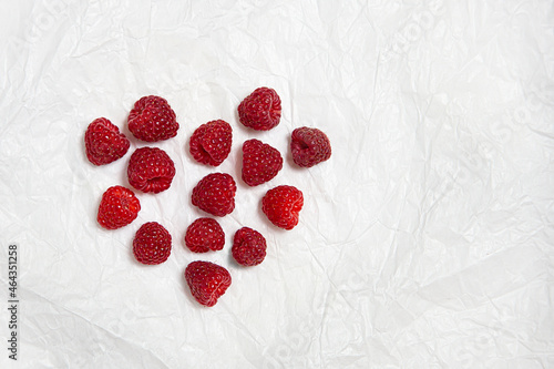 Raspberry berries are laid out with a heart on a white background.