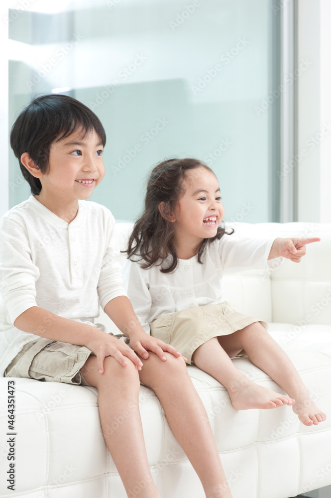 リビングのソファに座る子供男女 リビングのソファに座る子供男女