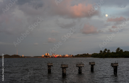 Dramatic image of a sunset over a Caribbean bay with a harbor lit by the sunset and moon over head, an$ piers in silhouette.