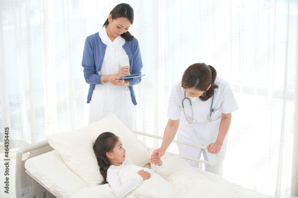病院ベッドの女の子を診察する女医と看護師 病院ベッドの女の子を診察する女医と看護師
