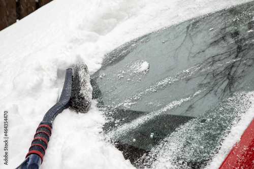 Snowdrift and brush on windshield of car. Cleaning car from snow. Concept of bad weather, snow storm