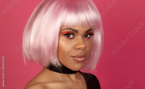 Beautiful young black woman with pink lipstick. Glamour fashion model with bright make-up, at studio. Closeup beauty portrait. Model with creative coloured bob hairstyle.