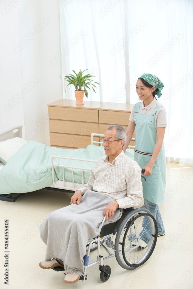 車椅子の老人と介護ヘルパー