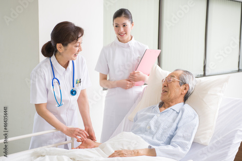 ベッドの入院シニア患者を診察する女医と看護師