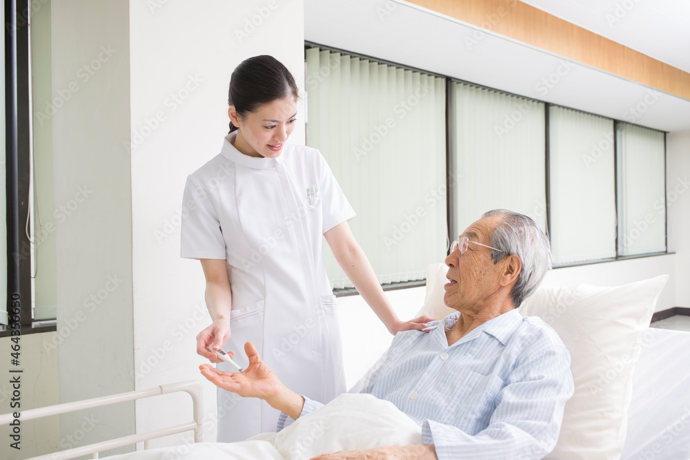 ベッドの入院シニア患者と看護師 ベッドの入院シニア患者と看護師