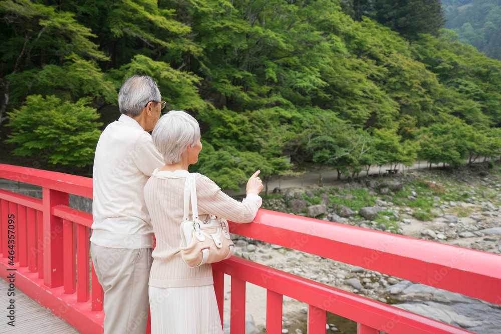 橋の欄干から風景を見るシニア夫婦 橋の欄干から風景を見るシニア夫婦