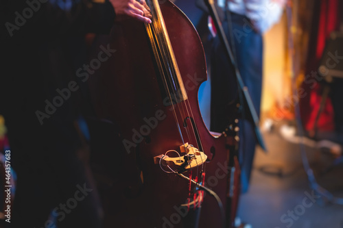 Concert view of a contrabass violoncello player with vocalist and musical band during jazz orchestra band performing music, violoncellist cello jazz player on the stage