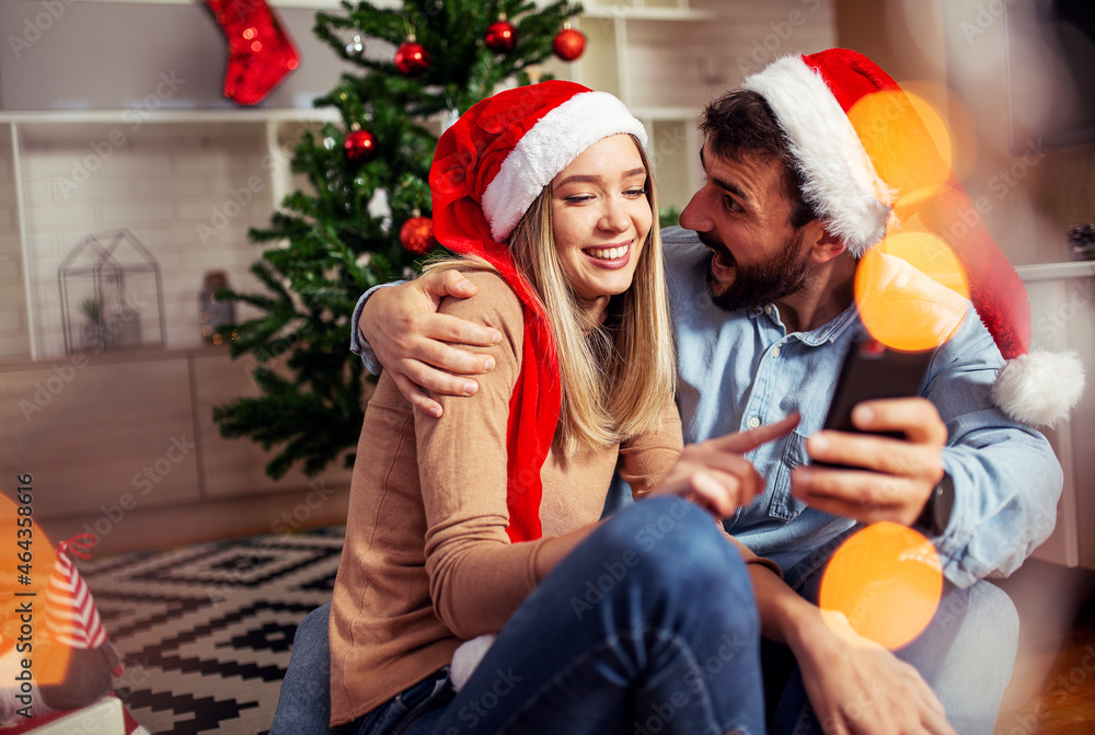 Fototapeta premium Couple using phone at Christmas time