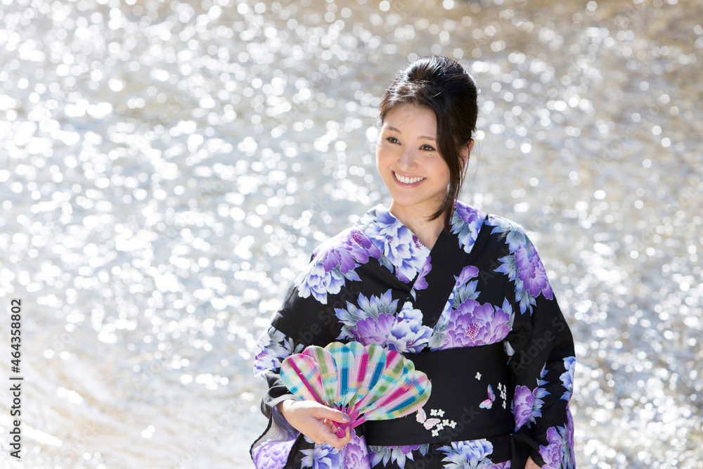 川の水面と風鈴を持つ浴衣の女性