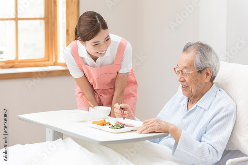 食事を手伝う介護士女性とシニア男性 photo