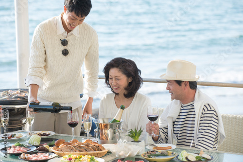 海岸のレストランで母にワインを注ぐ息子 photo