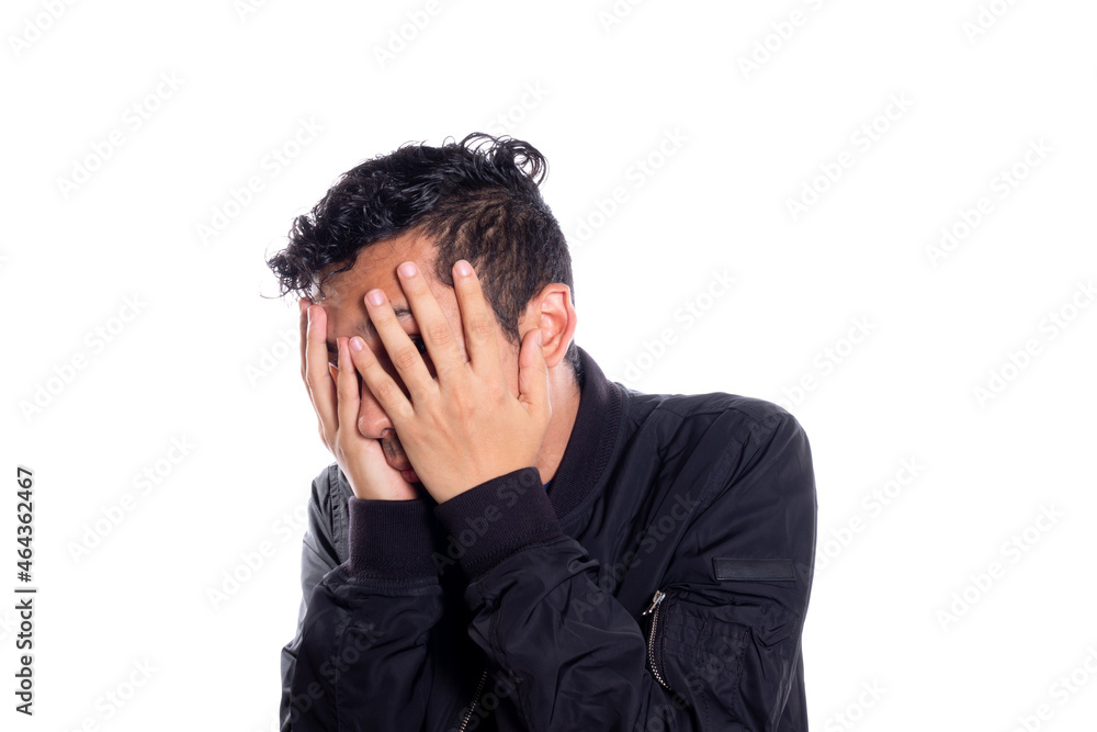 Embarrassed man covering his face with his hands. White background. Man covering his face and looking at camera through fingers. Embarrassed man covering his face with his hands. White background. Man covering his face and looking at camera through fingers.