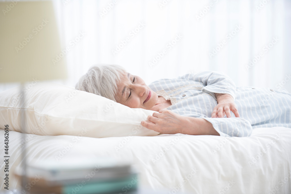 ベッドで睡眠するシニア女性 ベッドで睡眠するシニア女性