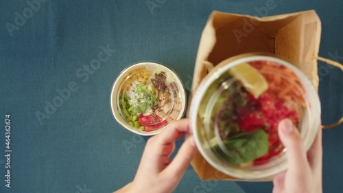 Food delivery of traditional Hawaiian cuisine. Packaging cooked poke bowls into paper bag. Healthy vegetarian eating. Asian vegan raw meal. Delivery services during coronavirus pandemic. photo