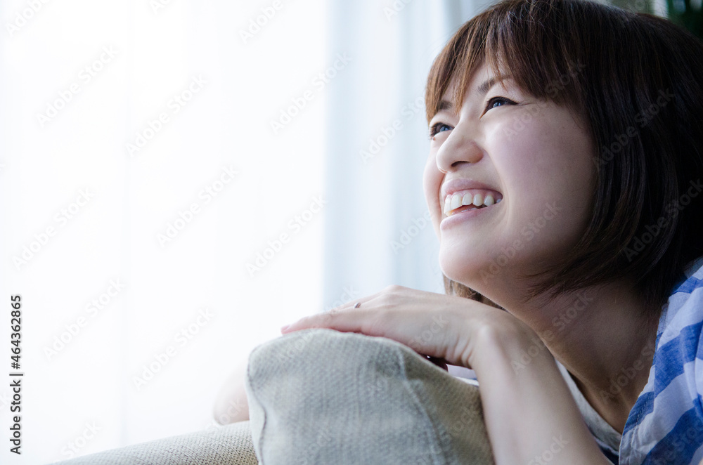 ソファに手を置いて笑う女性 ソファに手を置いて笑う女性