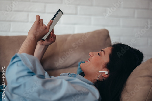 Woman using a smartphone while relaxing on the couch at home