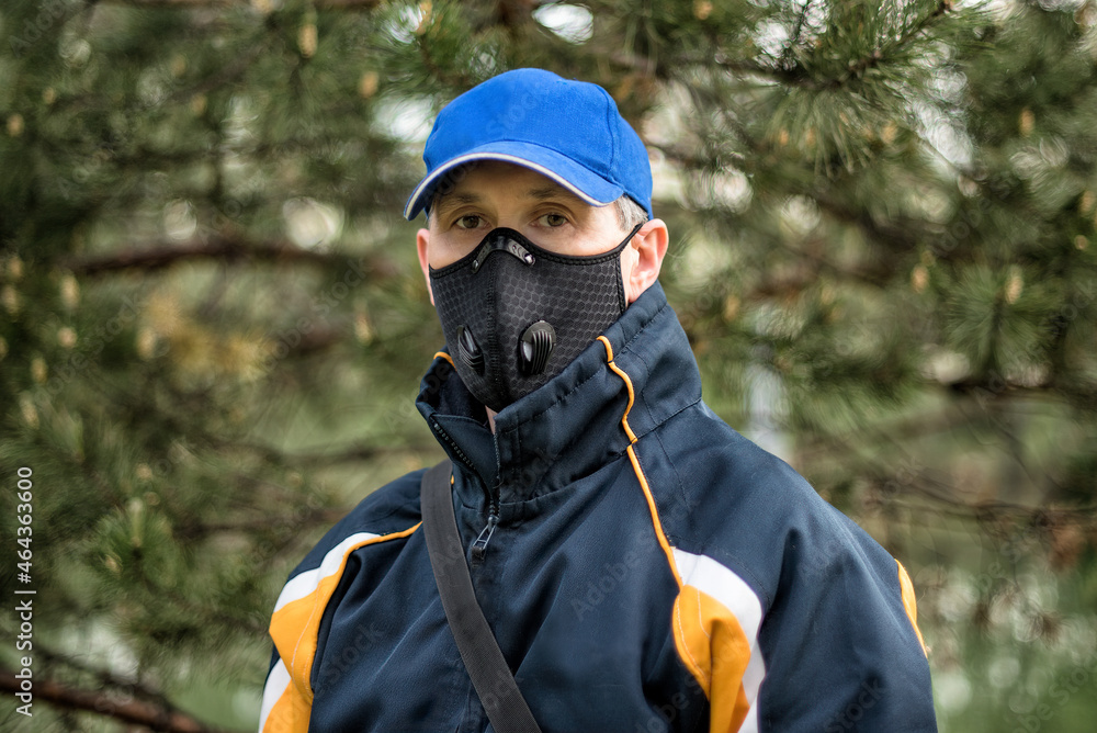 A man wearing respirator mask and a cap outdoors. A man wearing respirator mask and a cap outdoors.