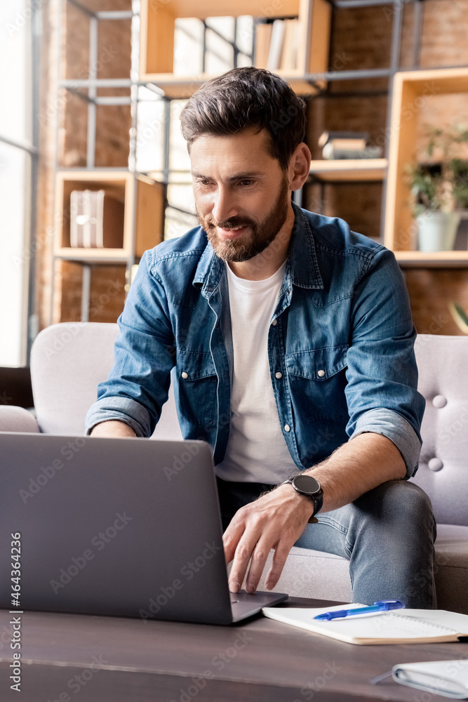 Smiling man working on laptop, checking email, writing message in social network Smiling man working on laptop, checking email, writing message in social network