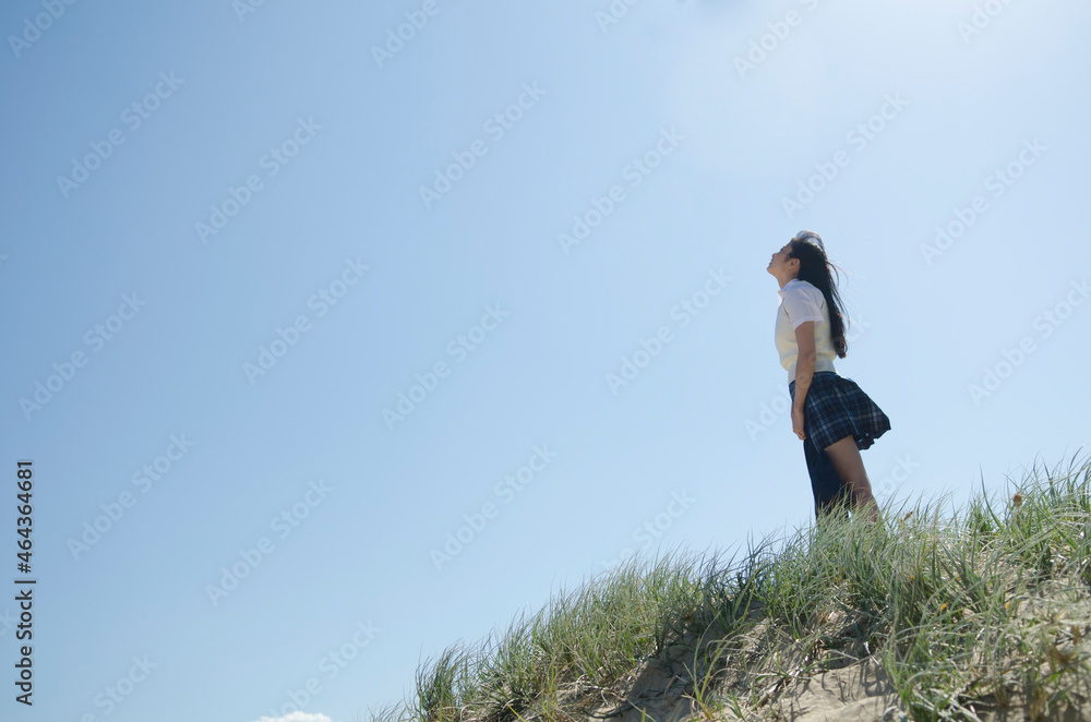 草むらに立って空を見上げている制服姿の女の子 ,ノースカールカールビーチ、シドニー