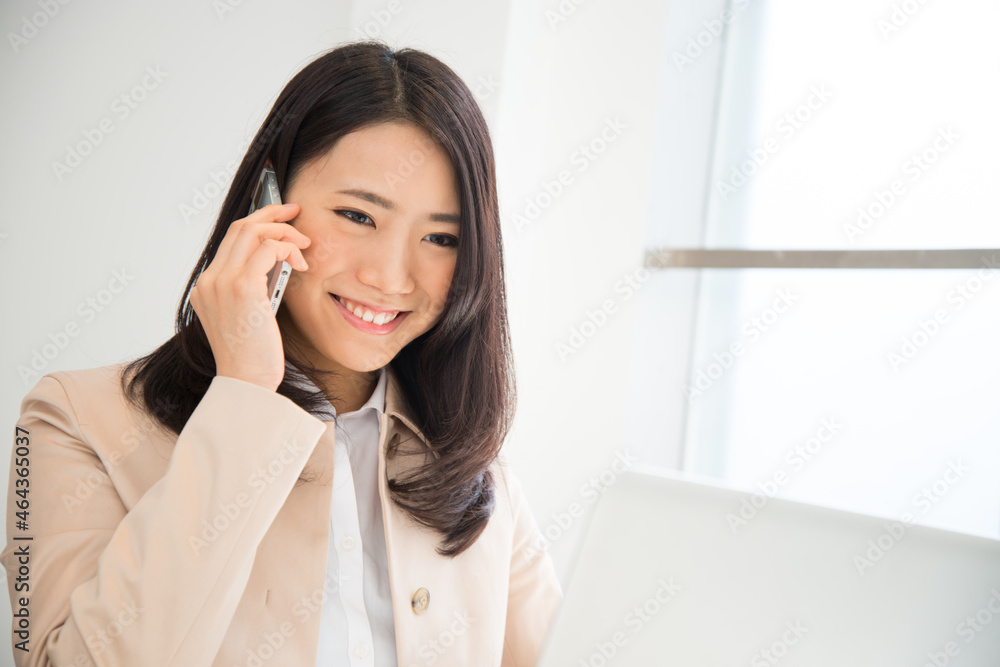 ノートパソコンを見ながら電話をしている女性 ノートパソコンを見ながら電話をしている女性