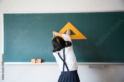 黒板にチョークで線を書く小学生の女の子 photo