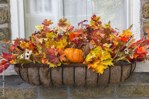 A Fall Themed Moss Lined Window Flower Box Filled With Orange, Red and  Yellow Leaves and Pumpkins photo