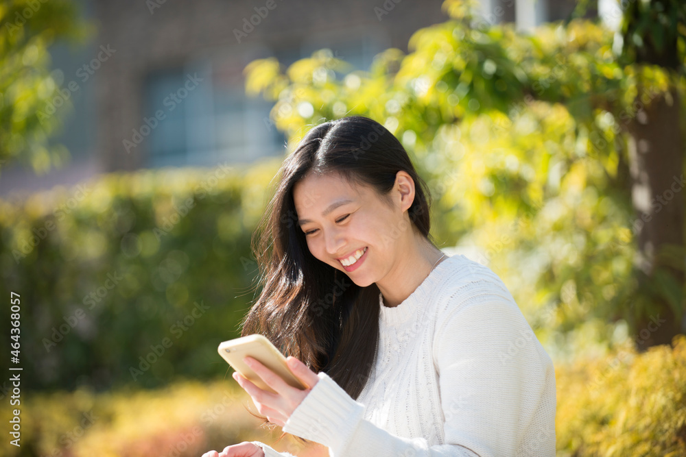 笑顔でスマホをいじっている女性