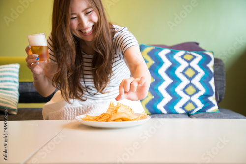 部屋でポテトチップをつまんでいる女性 photo