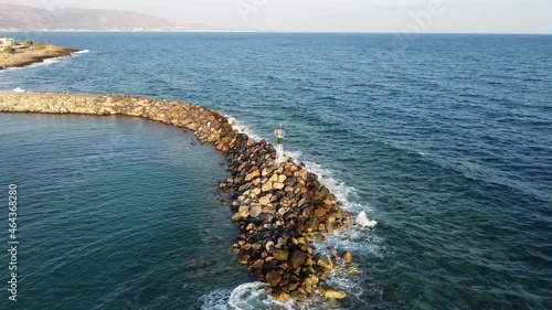 Aerial view of the coast near the lighthouse in Greece on the island of Crete. The drone captures the texture of the rocks as the waves crash against it. Drone Shot 4k