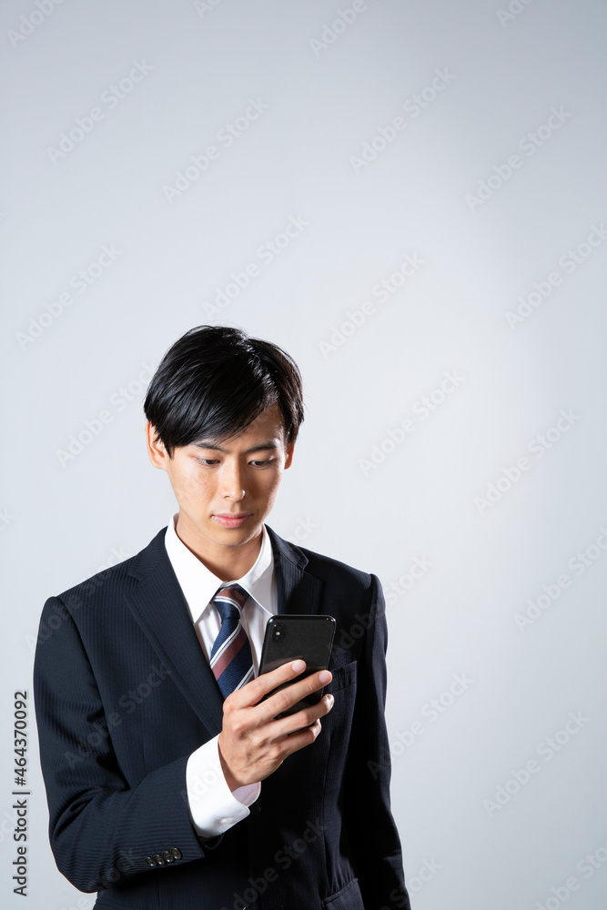 スマホを確認するスーツ姿の20代男性