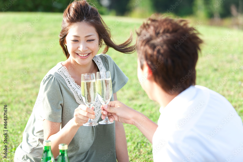 芝生に座って乾杯しているカップル 芝生に座って乾杯しているカップル