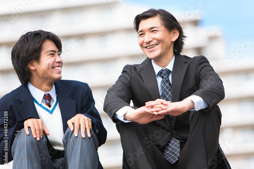 笑顔で会話する男子中高生とスーツ姿の父親 photo