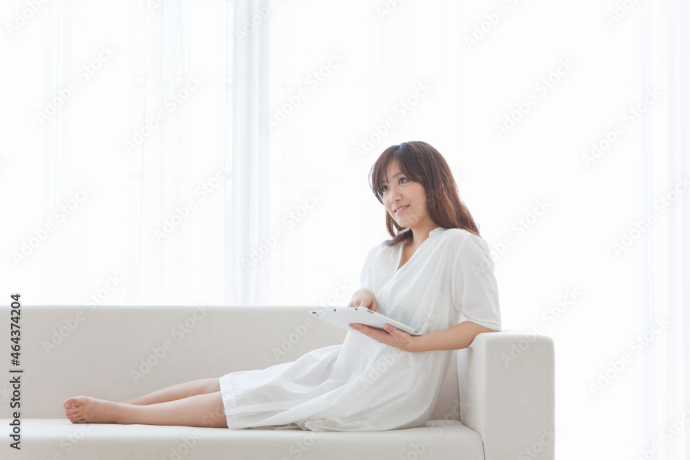ソファーに座ってiPadを操作する女性 ソファーに座ってiPadを操作する女性