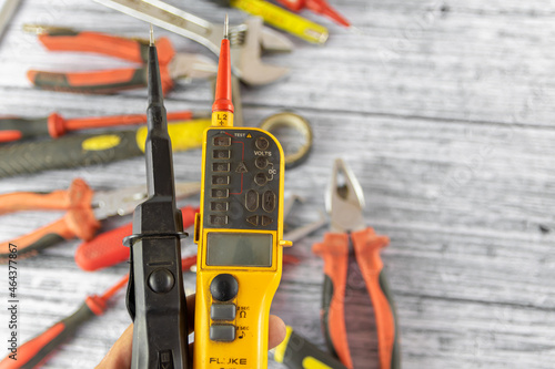 Probe voltage tester with repairing tools and instruments on the background photo