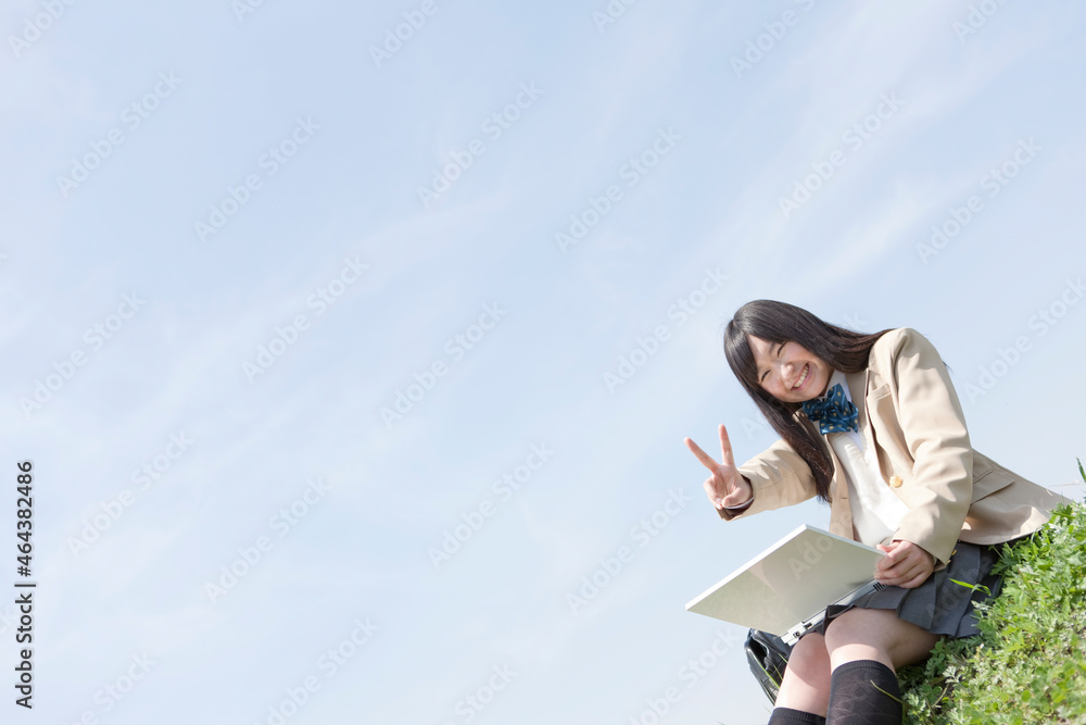 土手でノートパソコンを開く女子高生 土手でノートパソコンを開く女子高生